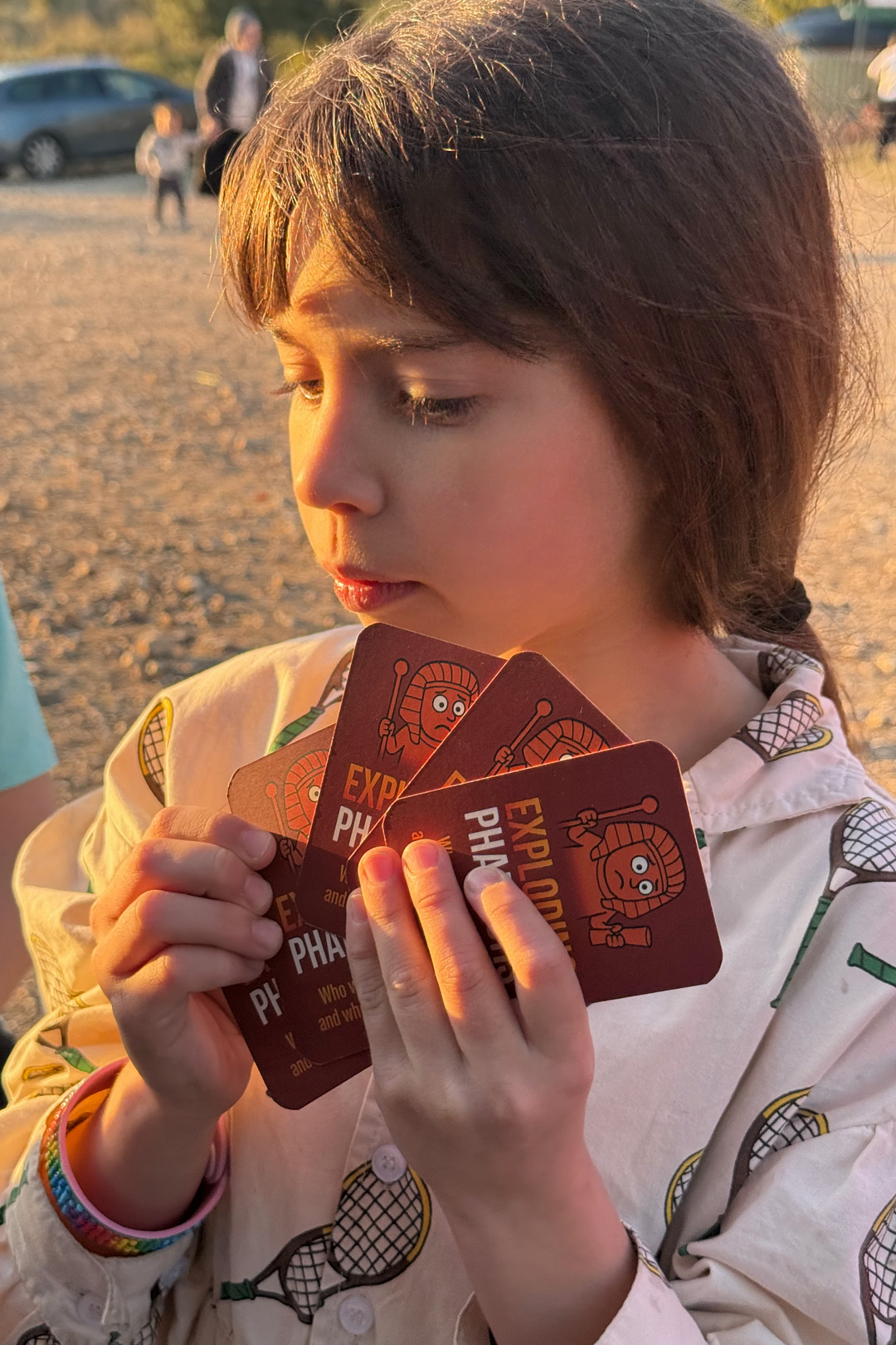 ילדה מחזיקה קלפים מהמשחק Exploding Pharaohs, בהשראת מכות מצרים